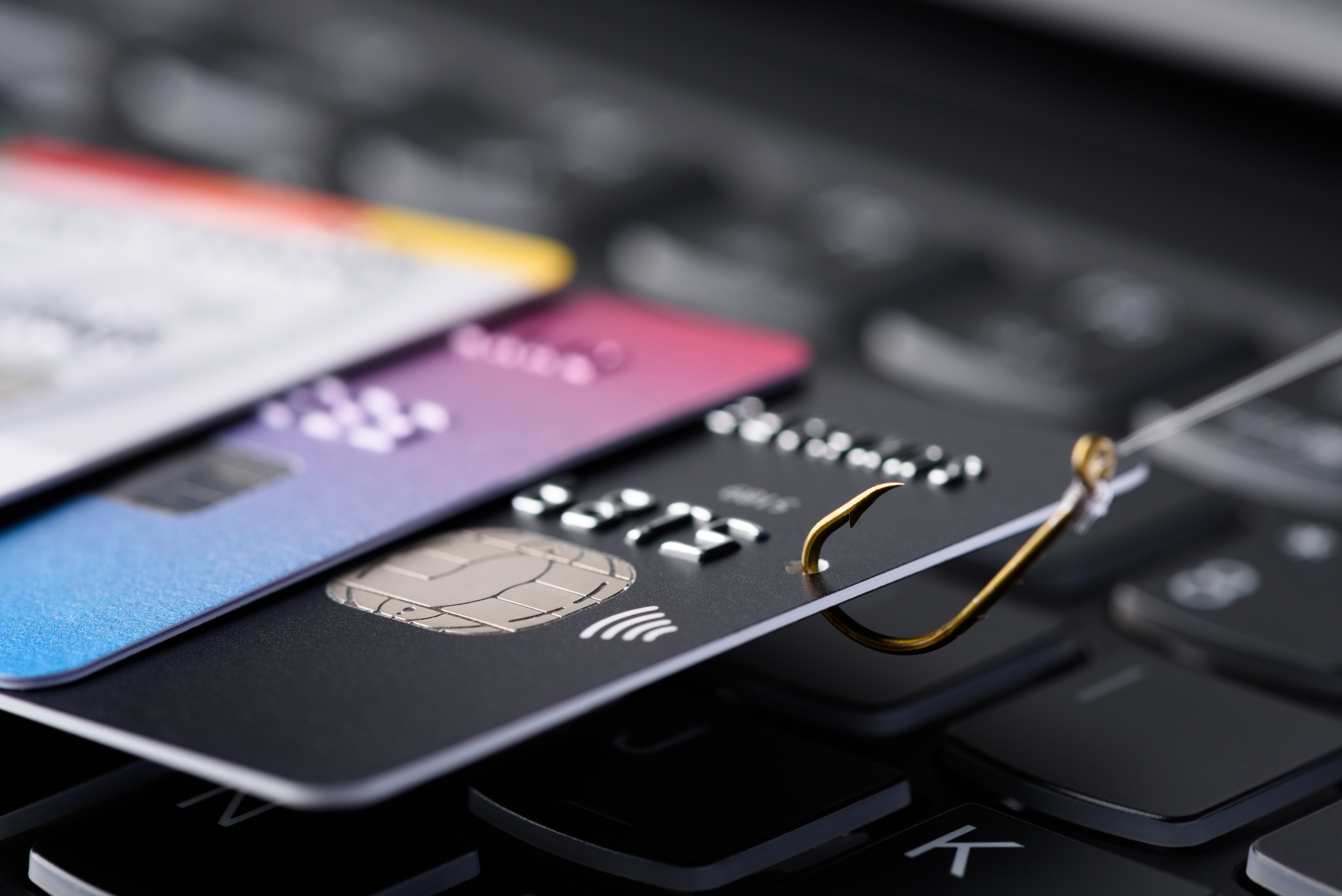 A stack of credit cards resting on a computer's keyboard