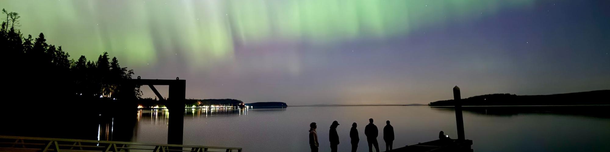 Group of people on a dock at Sequim Bay State Park watching the Northern Lights