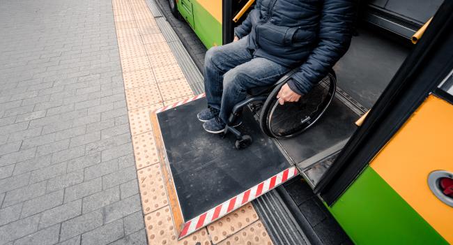 A person in a wheelchair exiting a bus via a ramp